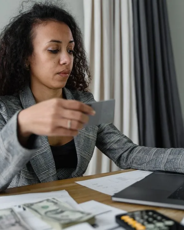 Mujer organizando sus pagos con tarjeta, calculadora y portátil